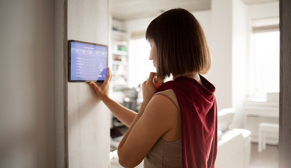 Frau bedient ein Touchpanel an der Wand zur Steuerung der Anlage