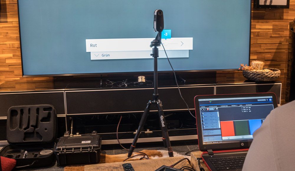 Messmikrofon auf Stativ vor einer Leinwand, daneben ein Laptop mit Kalibrierungssoftware