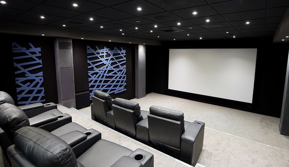 Heimkino mit Kinosesseln, großer Leinwand und Akustikpaneelen an den Wänden
