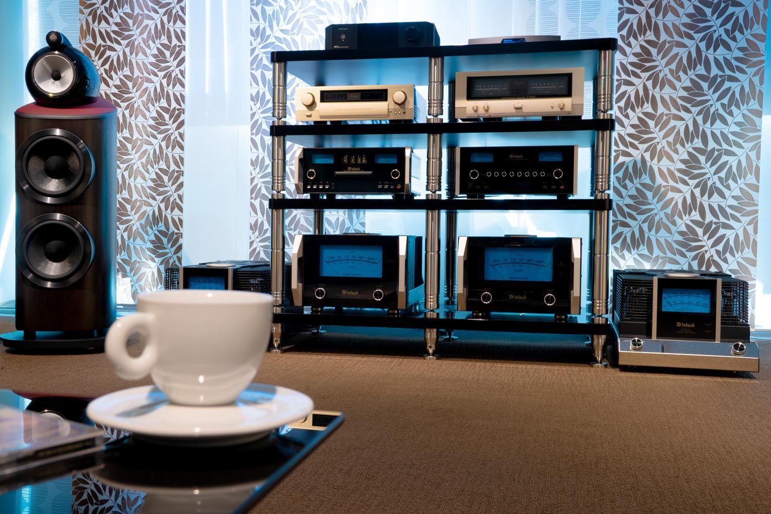 Die Bowers & Wilkins 801 Abbey Road Edition zusammen mit dem Rack und elektronischen Geräten mit einem Wohntisch und Kaffeetasse im Vordergrund.